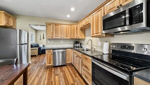 Una cocina moderna con armarios de madera, electrodomésticos de acero inoxidable y suelo de madera.