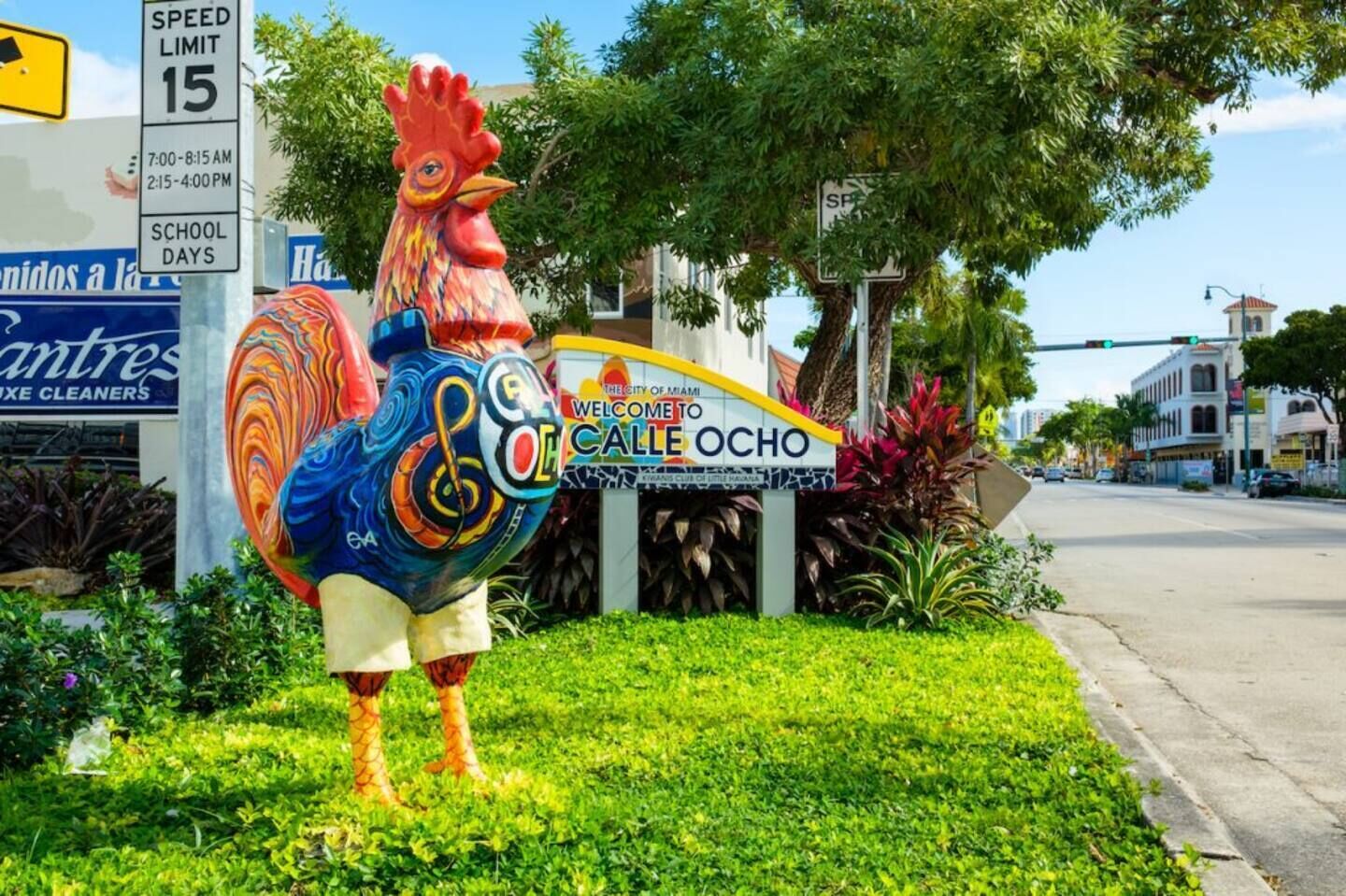 Una estatua colorida de un gallo frente a un edificio con un letrero que dice 'Calle Ocho'.
