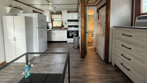A compact kitchen with white cabinetry, a central island, and a view into the adjacent bathroom. - The little cottage on the ct river (Haddam)