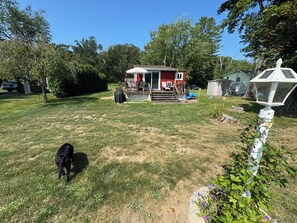 A backyard with a red house, a covered patio, and a white lantern.