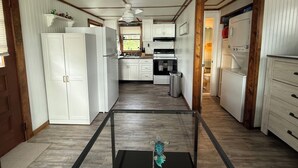 A kitchen with white cabinets, a stainless steel sink, and a black trash can. - The little cottage on the ct river (Haddam)