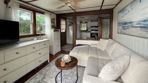 A cozy living room with a sofa, a TV, and a ceiling fan. - The little cottage on the ct river (Haddam)