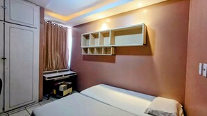 A bedroom with a bed, a wardrobe, a shelf unit, and a window with curtains.