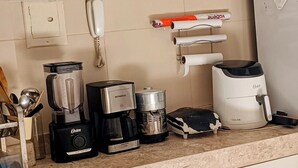 A kitchen with a gas stove, coffee maker, blender, and various kitchen utensils.