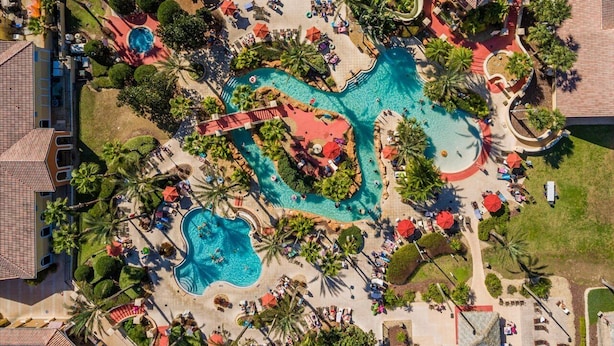An aerial view of a resort with multiple swimming pools, palm trees, and lounge areas. - Disney Family Resort: Home Theater, Pool & Free Parking/ Regal Palms Resort (Davenport)