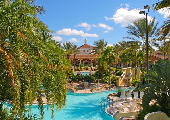 A resort with a large swimming pool, palm trees, and a building with a red roof.