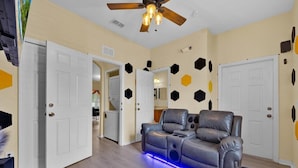 A living room with a leather sofa, a ceiling fan, and a wall with geometric patterns. - Disney Family Resort: Home Theater, Pool & Free Parking/ Regal Palms Resort (Davenport)