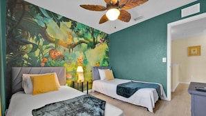 A room with two beds, a mural of a jungle scene, a ceiling fan, and a door leading to another room. - Disney Family Resort: Home Theater, Pool & Free Parking/ Regal Palms Resort (Davenport)