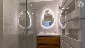 A modern bathroom with a glass-enclosed shower, a vanity with a wooden cabinet, and a large mirror above the sink. - LA PIERRE PONS - VOGLANS (VOGLANS)