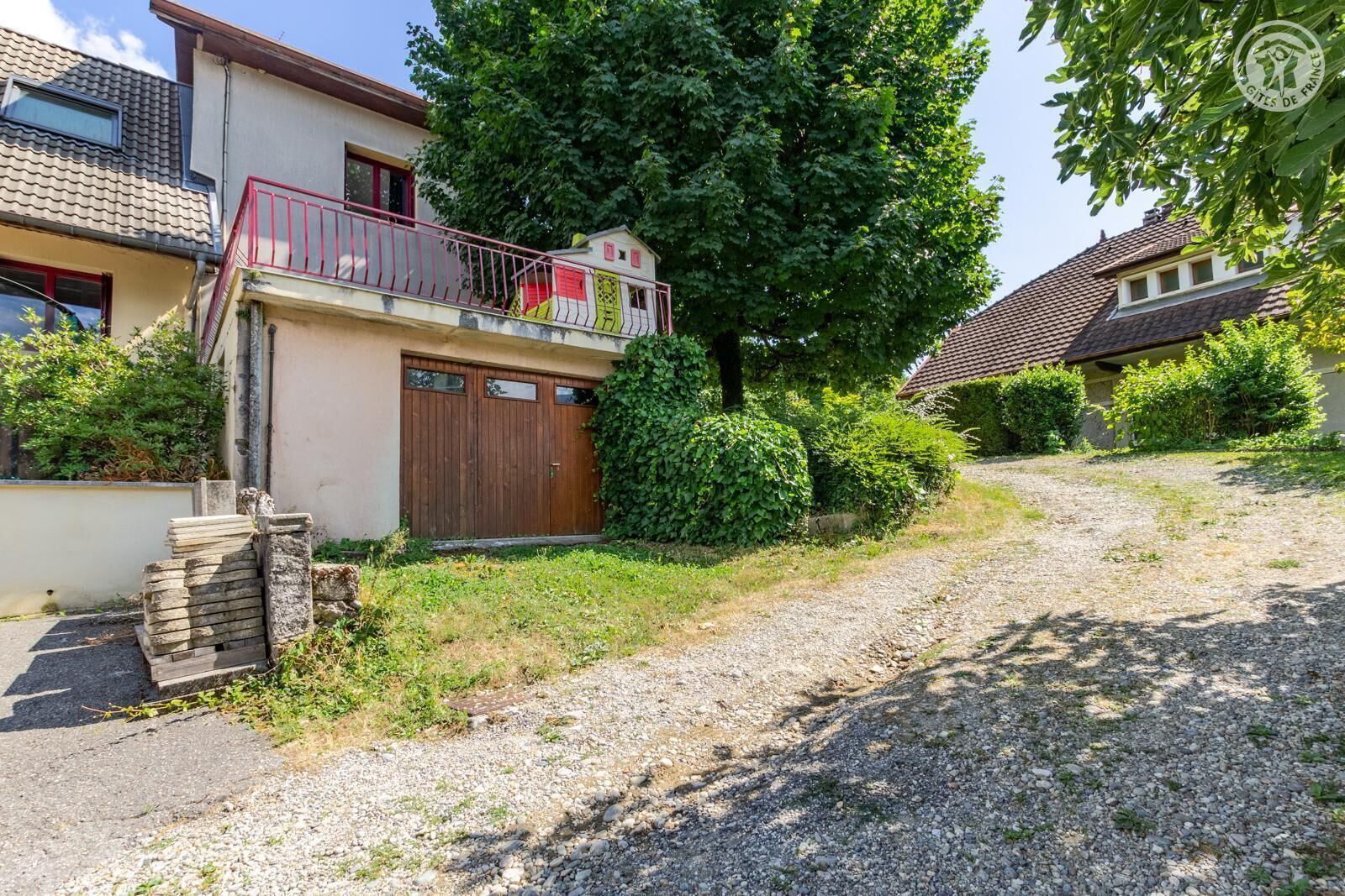 Een woonhuis met een huis van twee verdiepingen, een houten garagepoort en een grindpad.