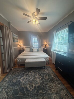 A bedroom with a bed, bedside tables, a ceiling fan, a window with blinds, and a dark-colored dresser. - Fall in Saratoga awaits (Saratoga Springs)