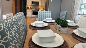 Un espace de vie compact comprenant un coin cuisine, un coin repas avec une table dressée pour deux personnes et un canapé.