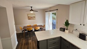 A modern kitchen with dark wood flooring, a marble island, and a dining area with yellow chairs. - Cozy retreat in Athens - convenient location, walk to Five Points, close to UGA. (Athens)