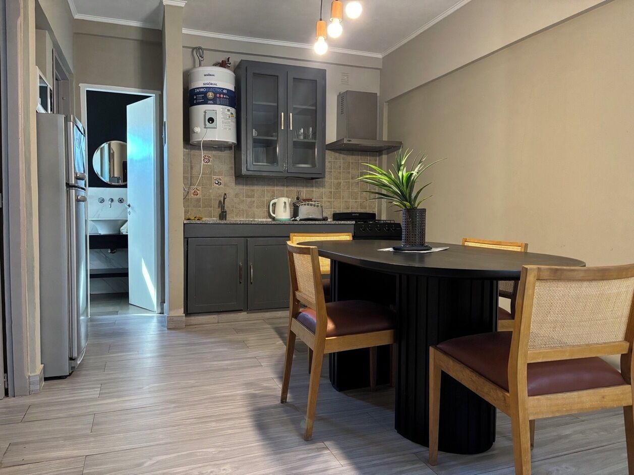 A modern kitchen with a dining table and chairs, a built-in oven, and a water heater.