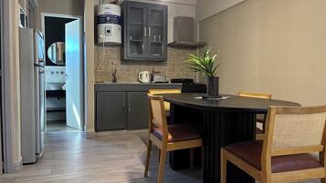 A modern kitchen with a dining table and chairs, a built-in oven, and a water heater.