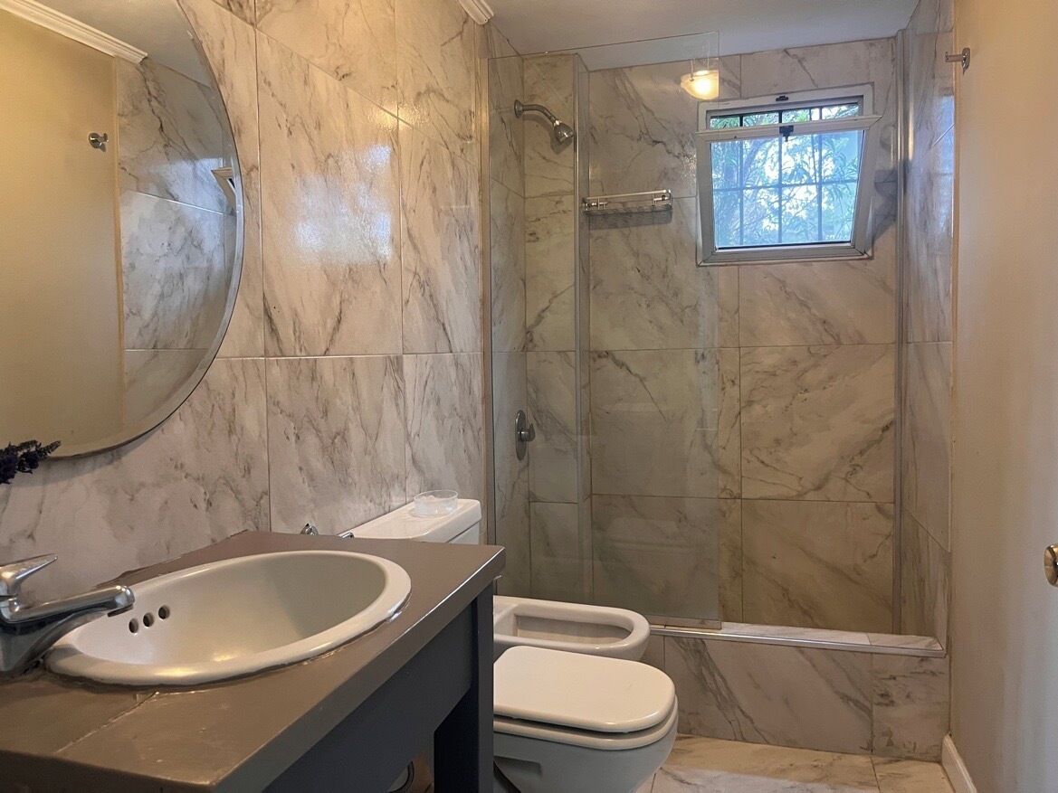 Une salle de bain avec un sol en marbre, un lavabo, des toilettes et une douche à parois de verre.