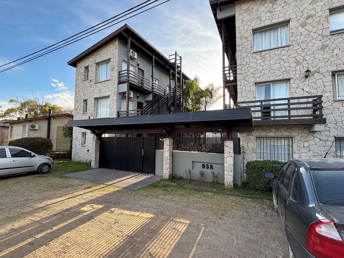 A two-story building with a stone facade, a black metal staircase, and a gated entrance.