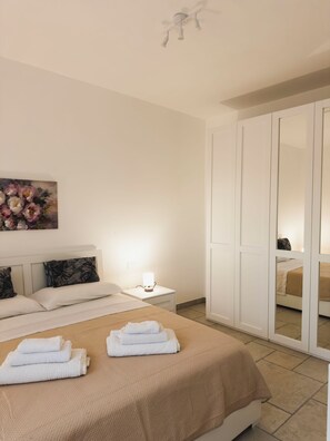A neatly arranged bedroom with a bed, bedside table, and a mirror cabinet. - Da Mèmela Trulli e Lamie in the beautiful countryside in Puglia suitable for families (Puglia)