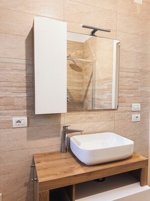 A bathroom with a wooden vanity, a white sink, and a mirror above the sink. - Da Mèmela Trulli e Lamie in the beautiful countryside in Puglia suitable for families (Puglia)