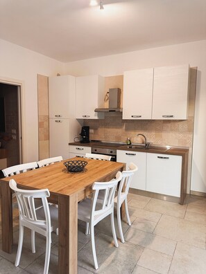 A modern kitchen with white cabinets, a wooden dining table, and white chairs. - Da Mèmela Trulli e Lamie in the beautiful countryside in Puglia suitable for families (Puglia)