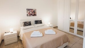 Een slaapkamer met een bed, nachtkastjes, een spiegel en een kledingkast.