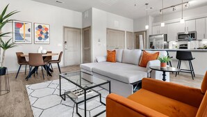 A modern living room with a sofa, coffee table, and dining area. - Modern 2-bedroom close to Airport & Downtown - Pool, Gym & Balcony (Austin)