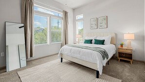 A bedroom with a bed, bedside table, lamp, and window with curtains. - Modern 2-bedroom close to Airport & Downtown - Pool, Gym & Balcony (Austin)