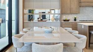 A modern kitchen with a large island, light wood cabinets, and a pendant light.