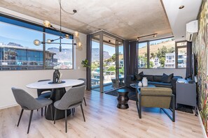 Una sala de estar moderna con comedor, ventanas amplias y vistas del paisaje circundante.