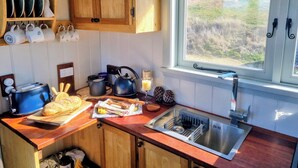 Una cocina con armarios de madera, una ventana con vistas a un campo, un fregadero y varios utensilios de cocina.