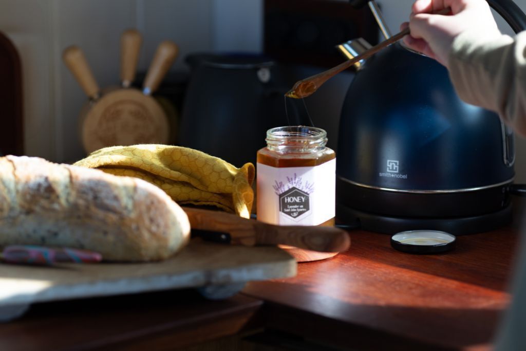 Un comptoir de cuisine avec une miche de pain, un pot de miel et une bouilloire.