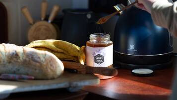 Un comptoir de cuisine avec une miche de pain, un pot de miel et une bouilloire.