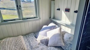 Un dormitorio con cama, almohadas, una ventana y un radiador.