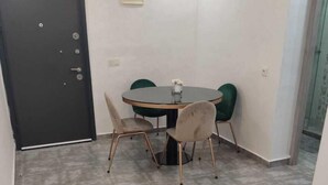 A dining area with a round table and four chairs, a black door, and a light fixture on the wall. - Chambre calme (Amizmiz)
