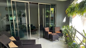 A modern outdoor seating area with wicker furniture and a variety of potted plants. - Delightful 2-bedroom condo with AC, 1/2 Block to 5th Ave and close to the beach! (Playa Del Carmen)