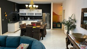 A modern kitchen with white cabinets, a stainless steel refrigerator, and a dining area with a table and chairs. - Delightful 2-bedroom condo with AC, 1/2 Block to 5th Ave and close to the beach! (Playa Del Carmen)