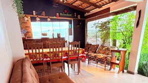 Un espace lounge moderne avec un long canapé marron, des chaises en bois et un bar à bières Heineken.