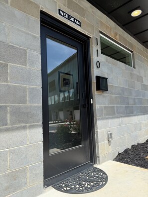 A building entrance with a black door, a 'WEE DRAM' sign, and the number '110' on the wall.