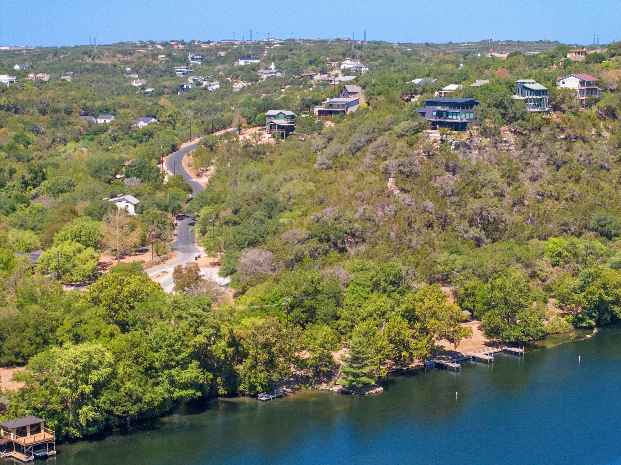 A residential area with houses on a hillside overlooking a body of water.