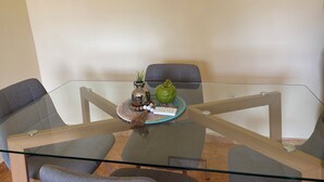 Ein moderner Glastisch mit Tabletts und Pflegeprodukten sowie einer Blumentopf.