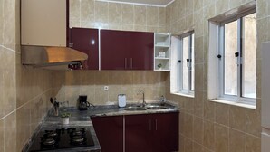 Eine kompakte Küche mit Gasherd, einer Kaffeemaschine und einem Fenster mit Aussicht.
