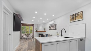 A modern kitchen with a large island, white cabinetry, and a built-in dishwasher.