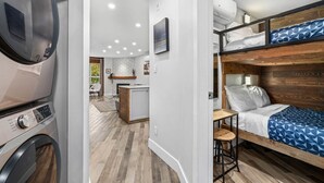 A compact RV interior with a kitchenette, a bunk bed, and a small dining area.