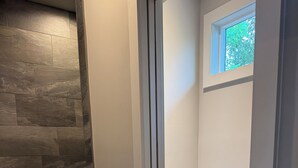 Een badkamer met een stenen muur, een wit toilet en een klein raam.