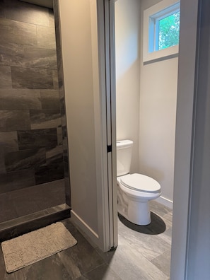 Un bagno con parete in pietra, un water bianco e una piccola finestra.