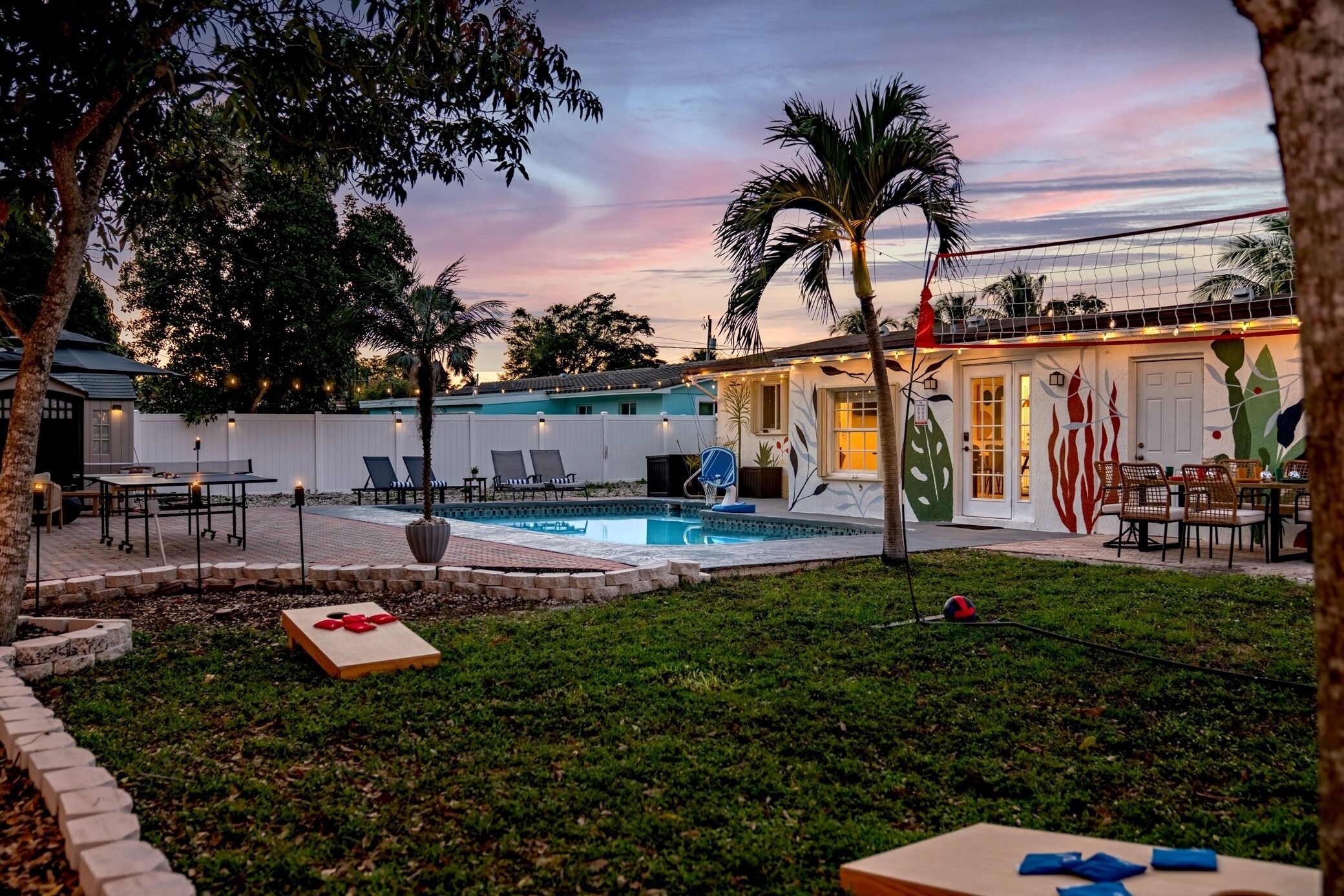 A backyard with a swimming pool, outdoor seating, and a building with a mural.
