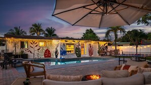 A poolside area with lounge chairs, a fire pit, and a dining table under an umbrella. - Sunny-Haven 3 Bedroom PoolVilla With GameRoom near the Beach & Shopping Centers (Plantation)