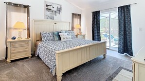 A bedroom with a bed, two bedside tables, a ceiling fan, and a view of the outdoors. - Smiling Disney Oasis heated pool home in Kissimmee with Game room. (Kissimmee)