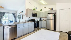 A modern kitchen with stainless steel appliances, a large island, and a view to the outside. - Smiling Disney Oasis heated pool home in Kissimmee with Game room. (Kissimmee)