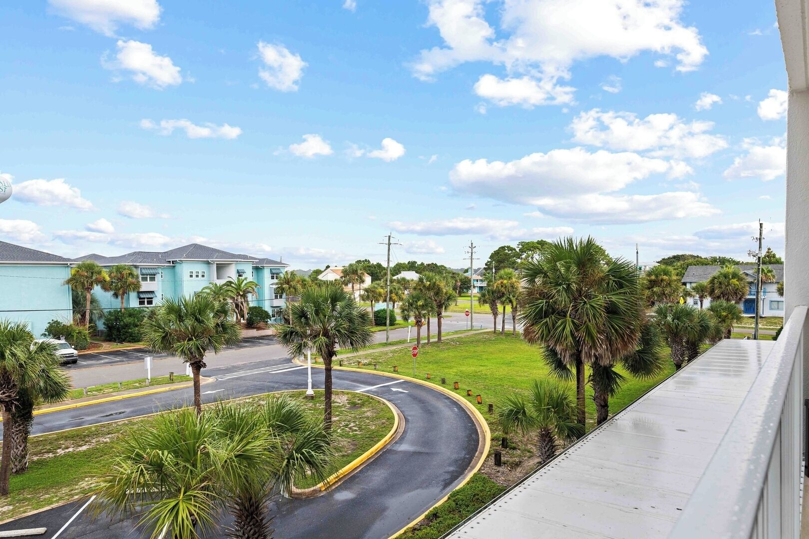 A residential area with a curved road, palm trees, and a blue building.